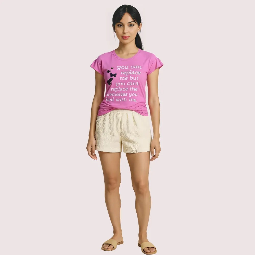 Woman wearing a pink t-shirt with text and white shorts on a light pink background