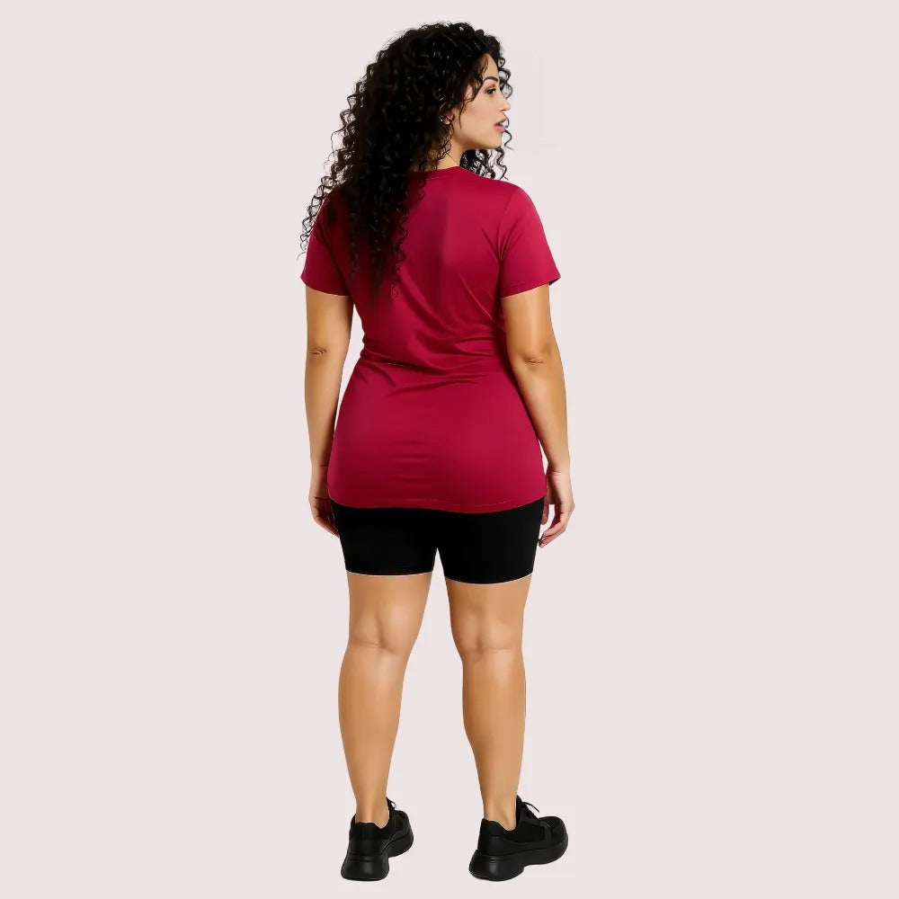 Woman wearing a red t-shirt and black shorts on a light pink background